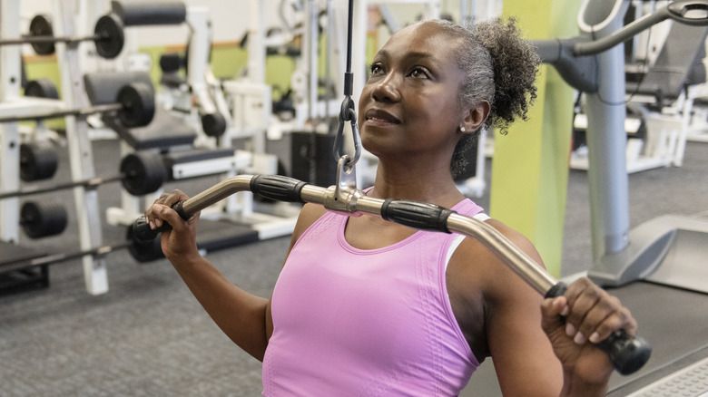 older woman doing lat pulldowns at the gym