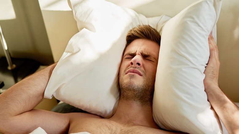 man lying in bed with headache