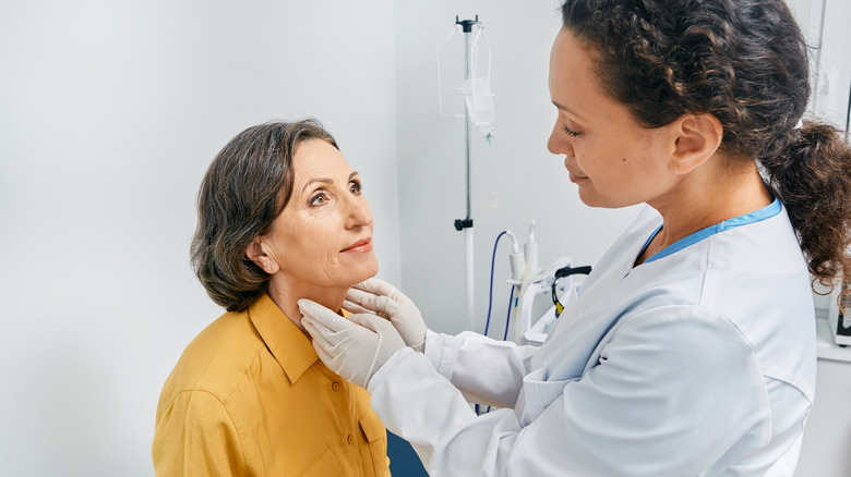 doctor examining woman's thyroid