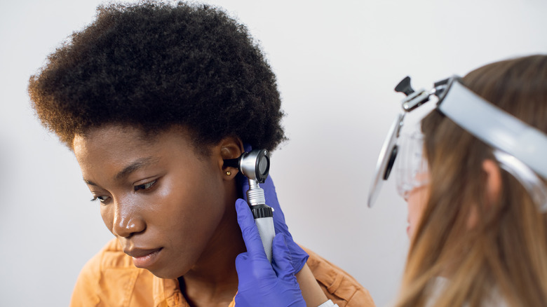 Young woman receiving doctor ear exam