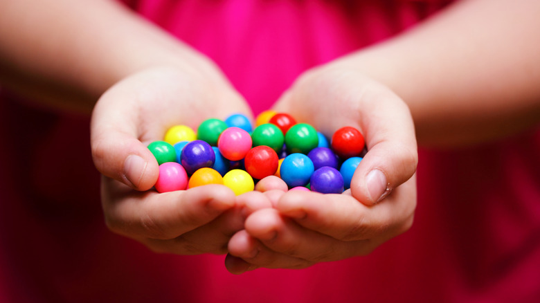 A child's hand holding multicolored candy