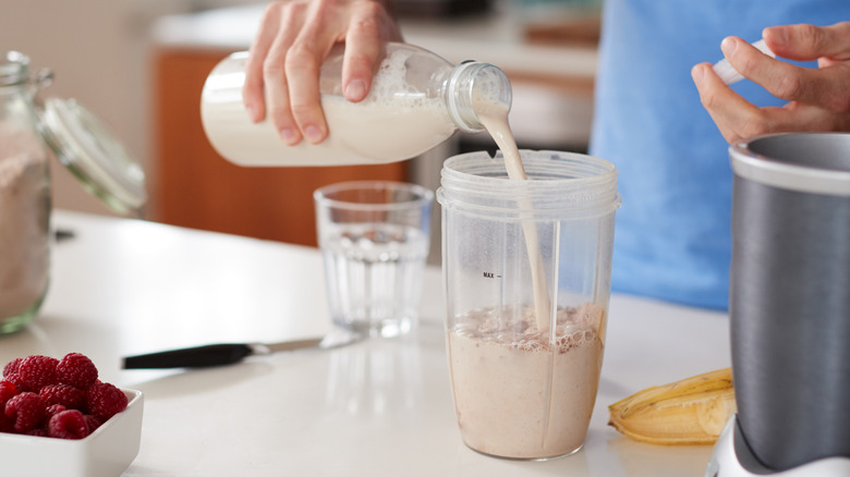 man blending oats and berries into a protein shake