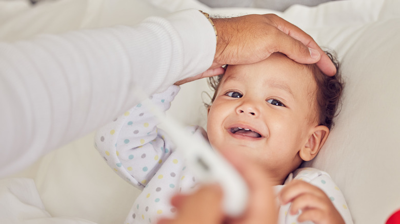 Hand feeling baby's forehead for fever