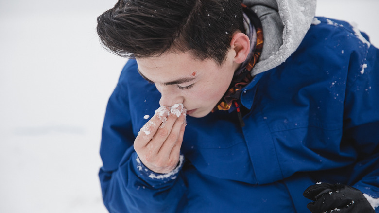 Teenage boy holding injured nose