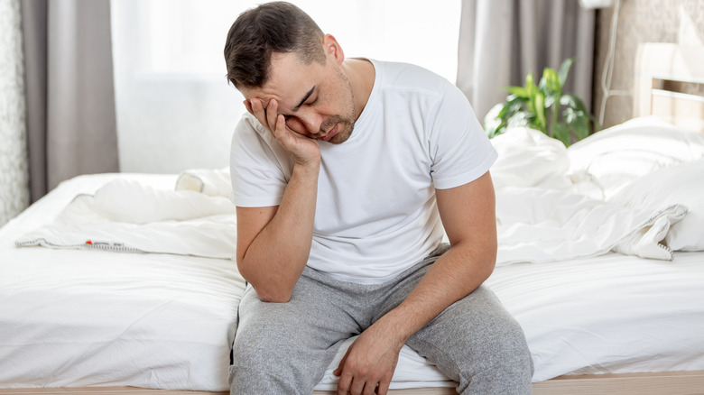 Tired man sitting on bed