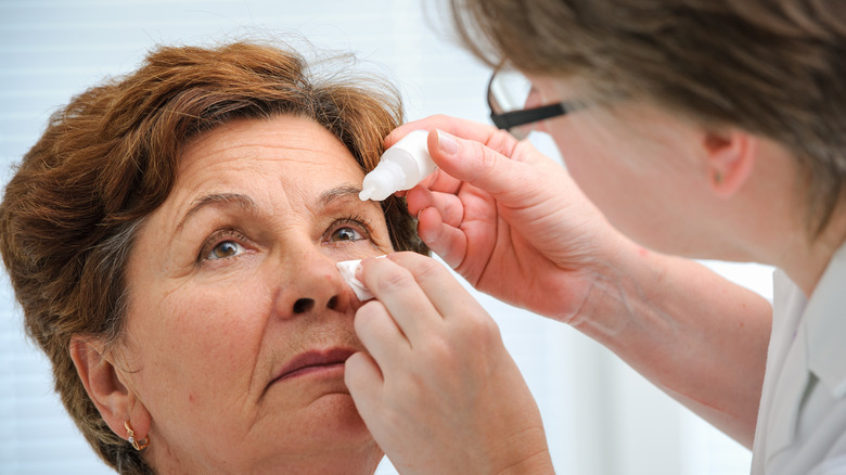 Patient receiving eye drops from doctor