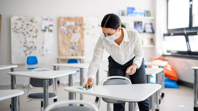 teacher disinfecting desks after lockdown