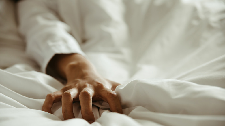Woman grasping sheets while having sex