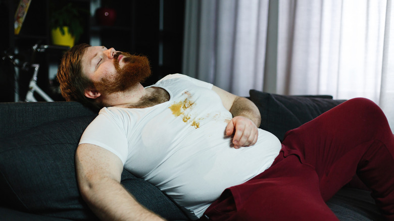 Man sleeping on couch after overeating