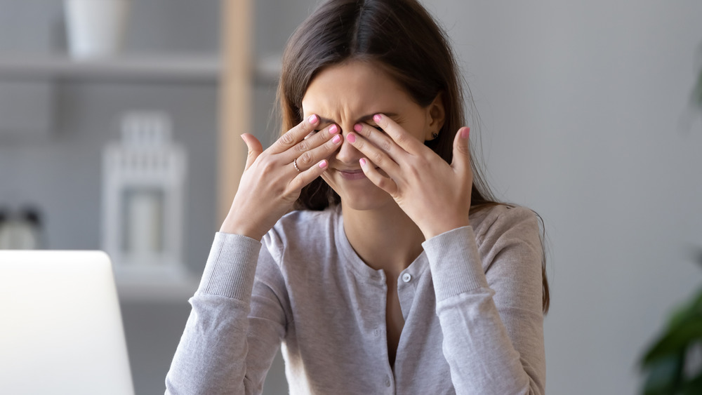 Woman sitting at desk rubbing her eyes