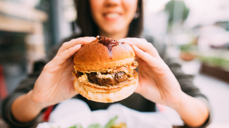 woman holding a beef burger close up