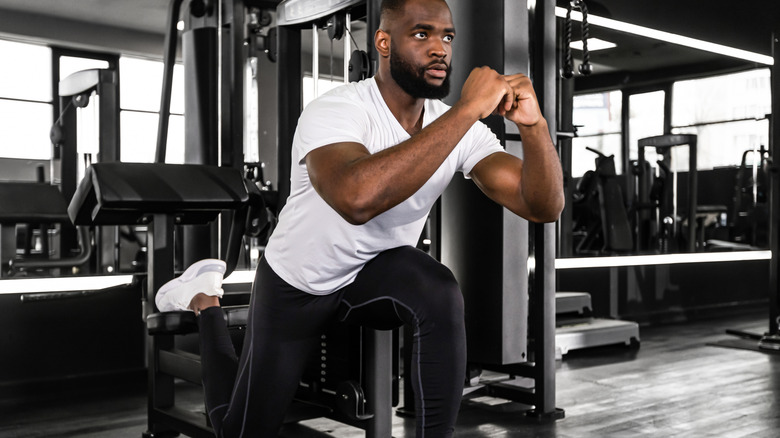 A fit man doing a Bulgarian split squat at the gym