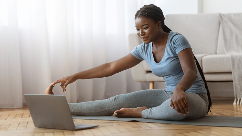 woman touching toes on Pilates mat