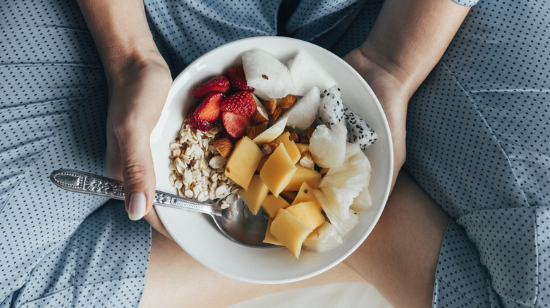 Person in pajamas holding breakfast bowl