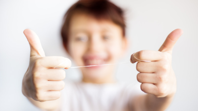 child with floss in hand