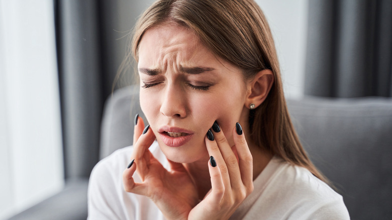 woman holding cheeks in pain