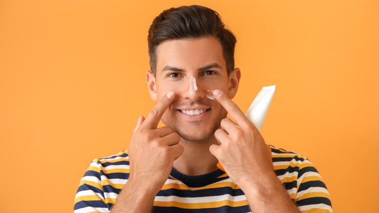 man putting on sunscreen