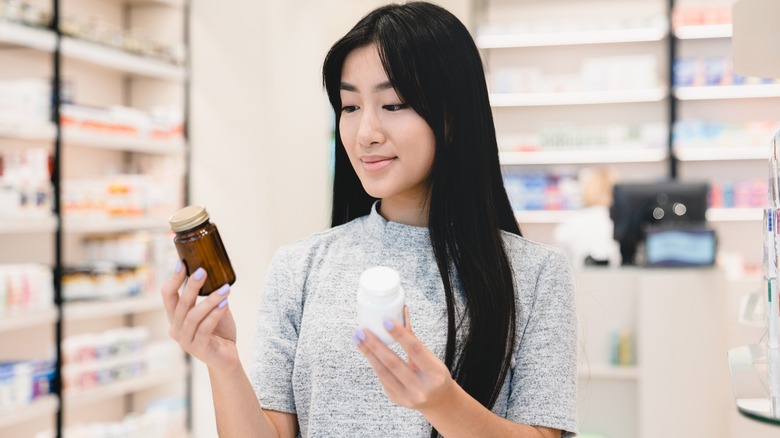 woman comparing two medication pill bottles