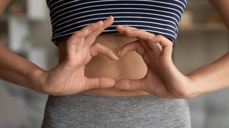 woman demonstrating digestive health with heart shaped hands over abdomen