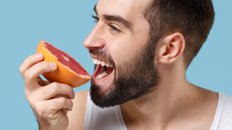 Young man biting grapefruit