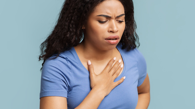 Woman with heartburn touching throat