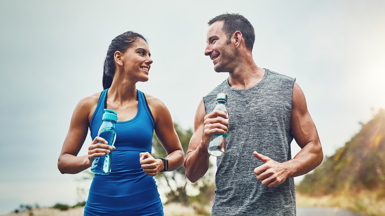 male and female athletes holding water bottles