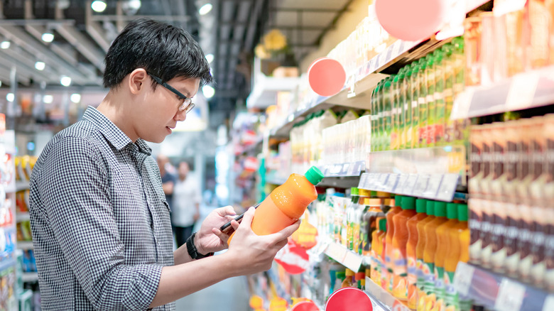 Man buying orange juice in supermarket