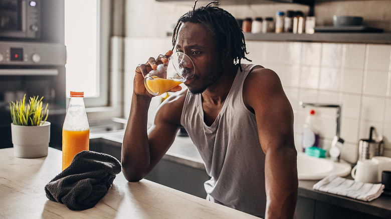 Man drinking glass of orange juice