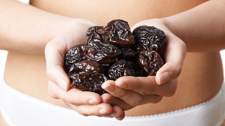 woman with two handfuls of prunes