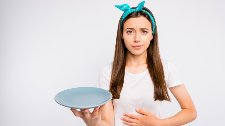 a woman holds empty plate - hungry