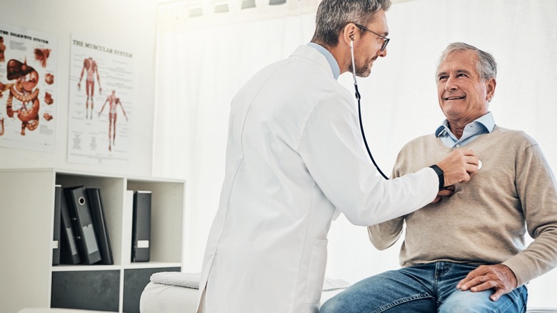 Doctor checking man's heart health with stethoscope