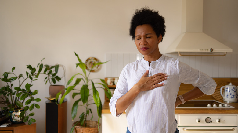 African American woman holding a hand on her chest due to heartburn pain