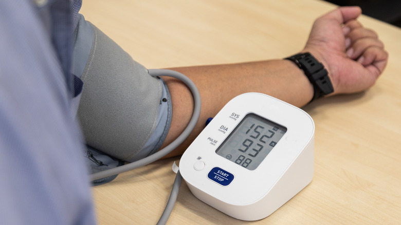 Man measuring his blood pressure at home with electronic device