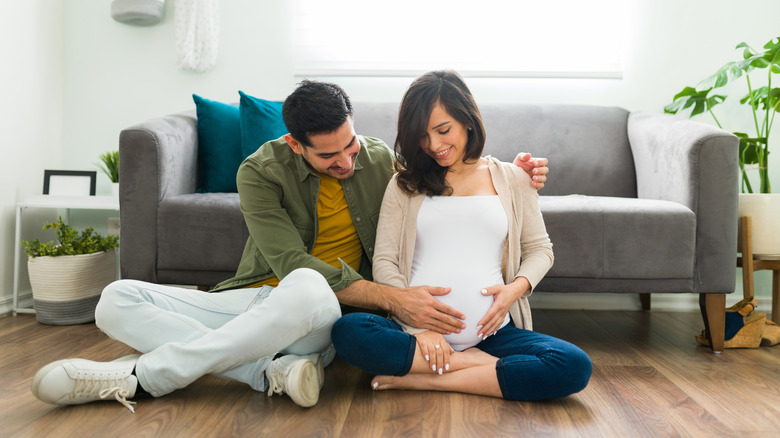 pregnant family sitting on living room floor