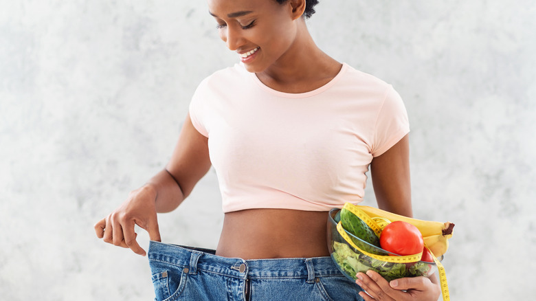 women with loose pants holding fruits 