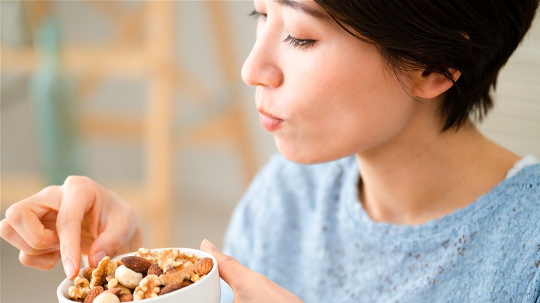 Person eating from cashew bowl