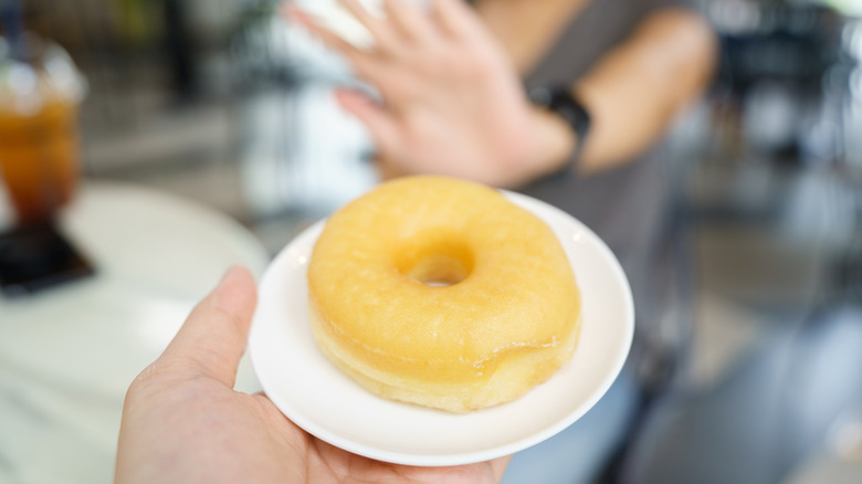 woman putting hand up to refuse doughnut