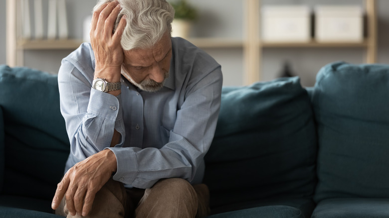 seated depressed man hand on head