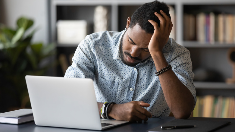 man head in hand asleep at laptop