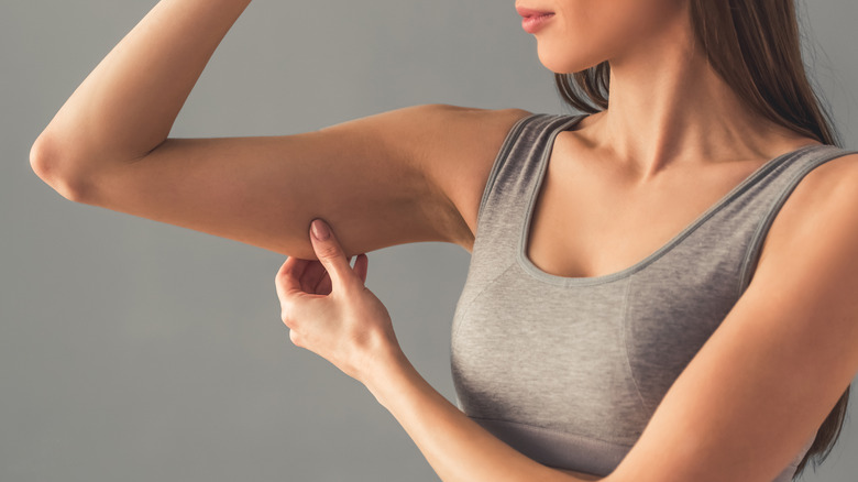 Woman pinching arm checking muscle loss