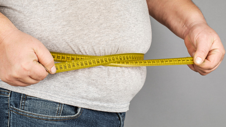 A man in jeans measuring his belly 