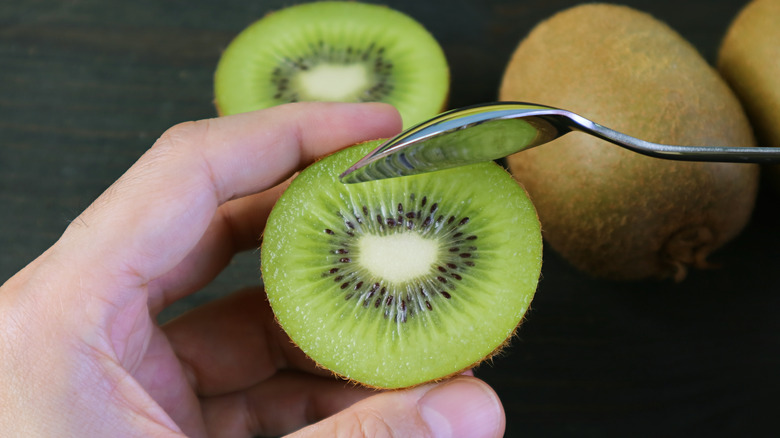 Hands holding spoonful of kiwi