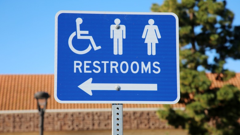 Blue metal restroom sign that's outdoors