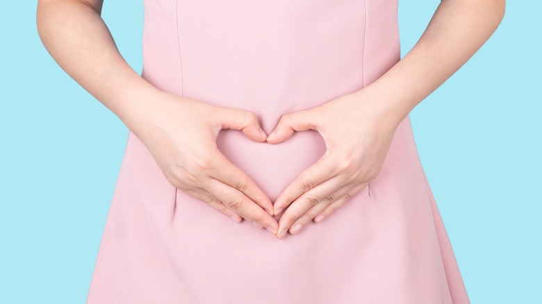 Hands making heart shape over stomach