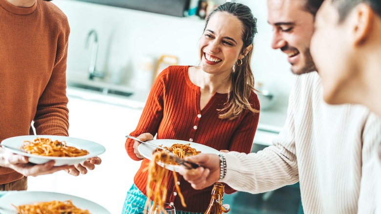 happy group of friends eating pasta