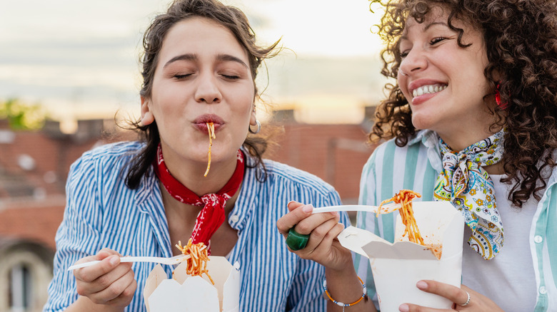 two friends enjoying pasta outdoors