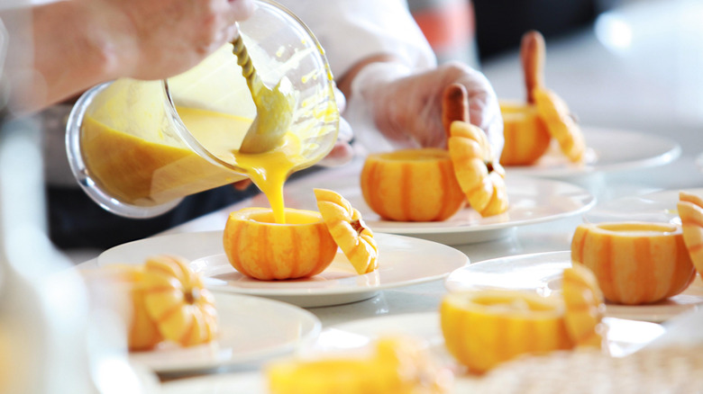 Chef portioning out pumpkin soup 