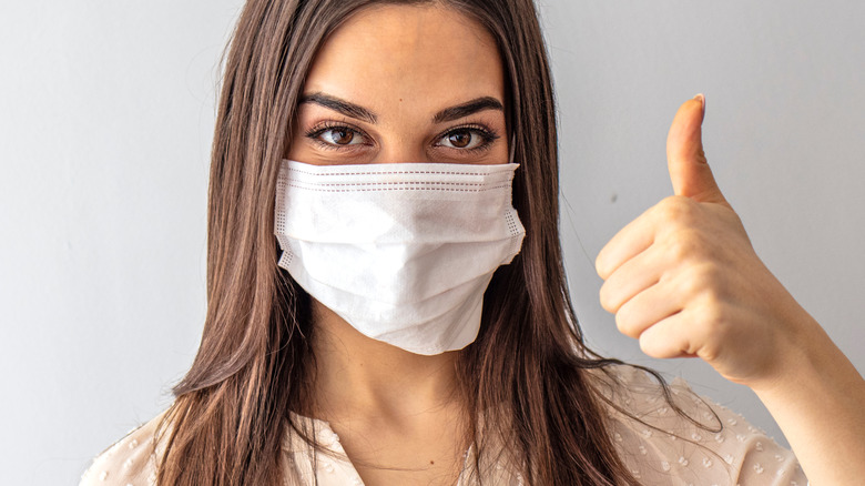 Woman wearing mask giving thumbs up