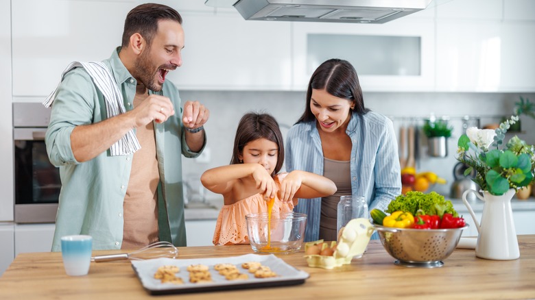 Young girl cracking eggs while making cookies