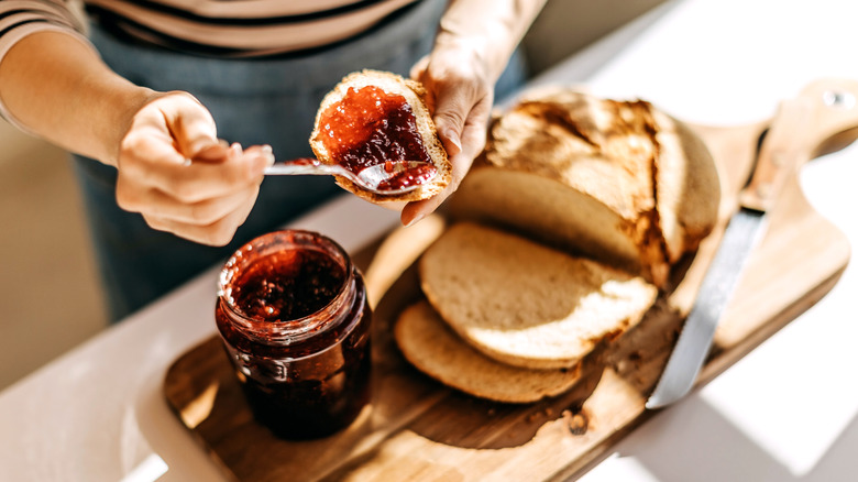 Woman spreading jam on sourdough bread